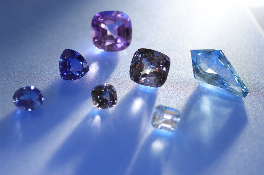 Collection of various blue and purple gemstones casting light and shadows in front of them
